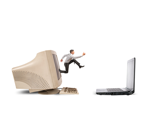 Businessman jumping from old computer to new laptop
