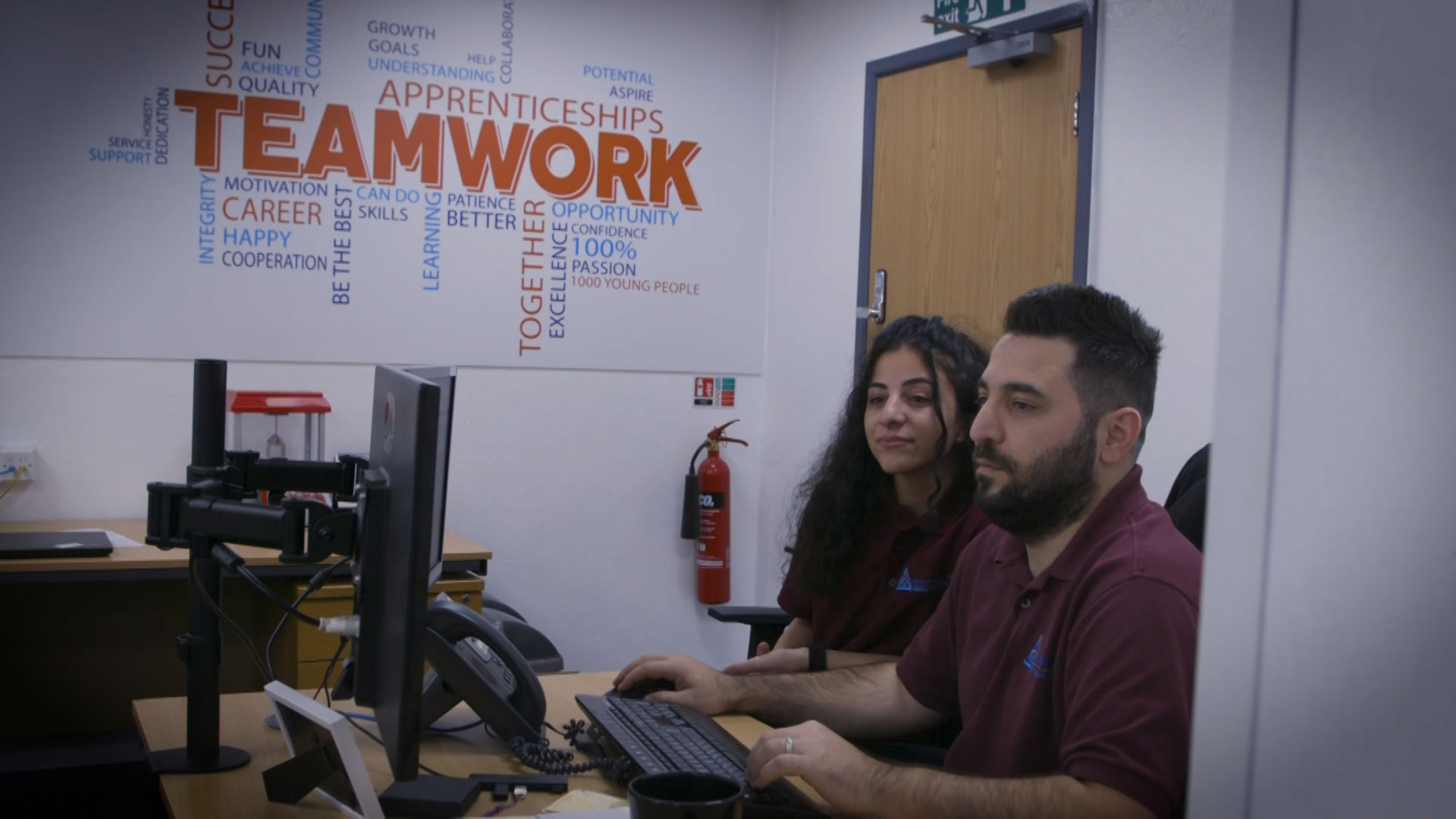 IT Technicians Working Next To Teamwork Sign